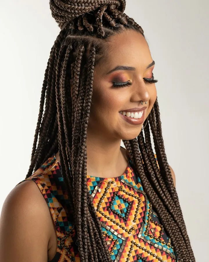 Woman with long knotless braids in a high half bun