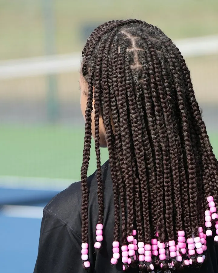 Knotless braids finished with pink beads, seen from behind